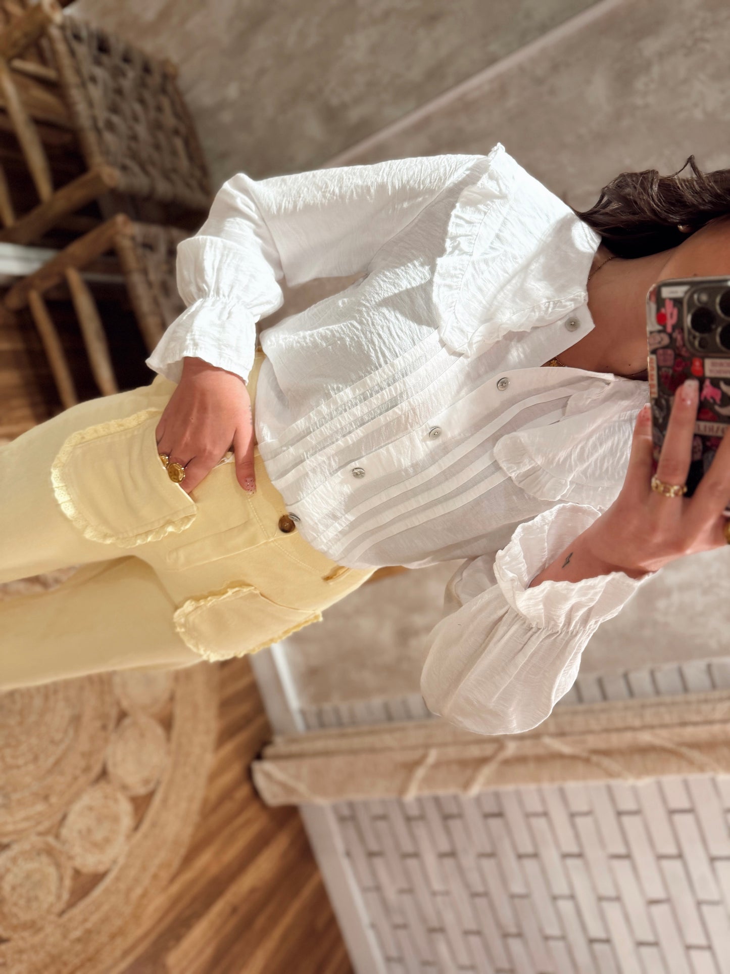 Camisa de tejido ligero con detalle de pliegues delanteros y cuello ancho con volantes.