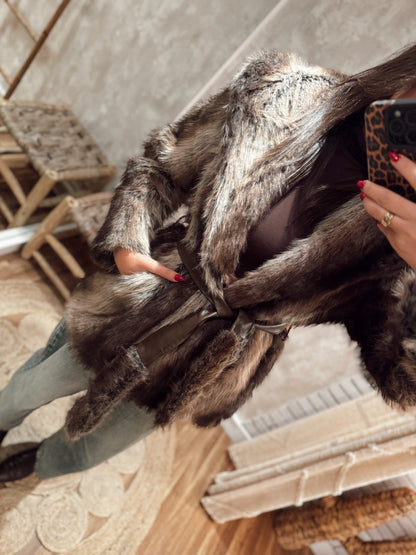 Casaco de pelo sintético em tons castanhos, com corte moderno e cinto para ajustar na cintura